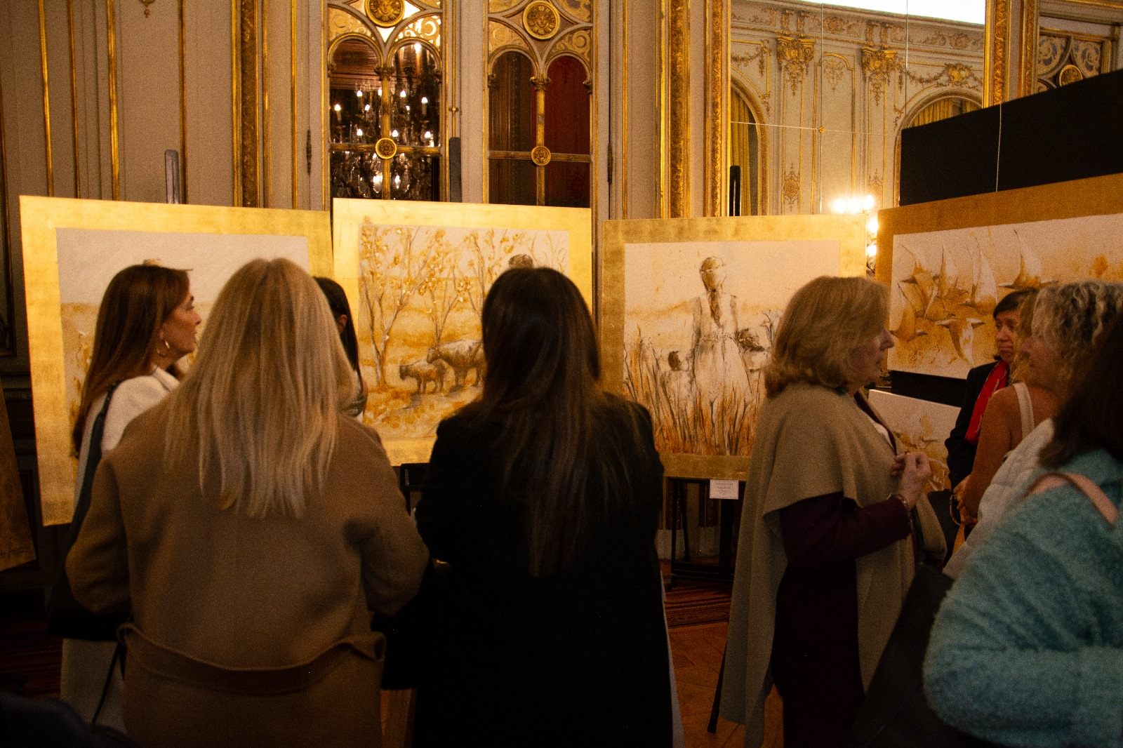 Público contemplando una serie de obras en tonos dorados