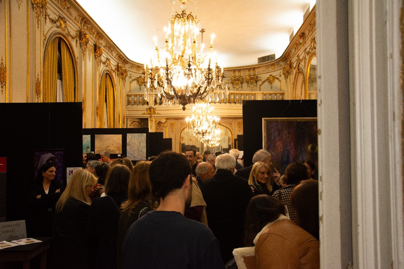 Salón principal del Palacio Paz colmado de asistentes bajo las arañas de cristal