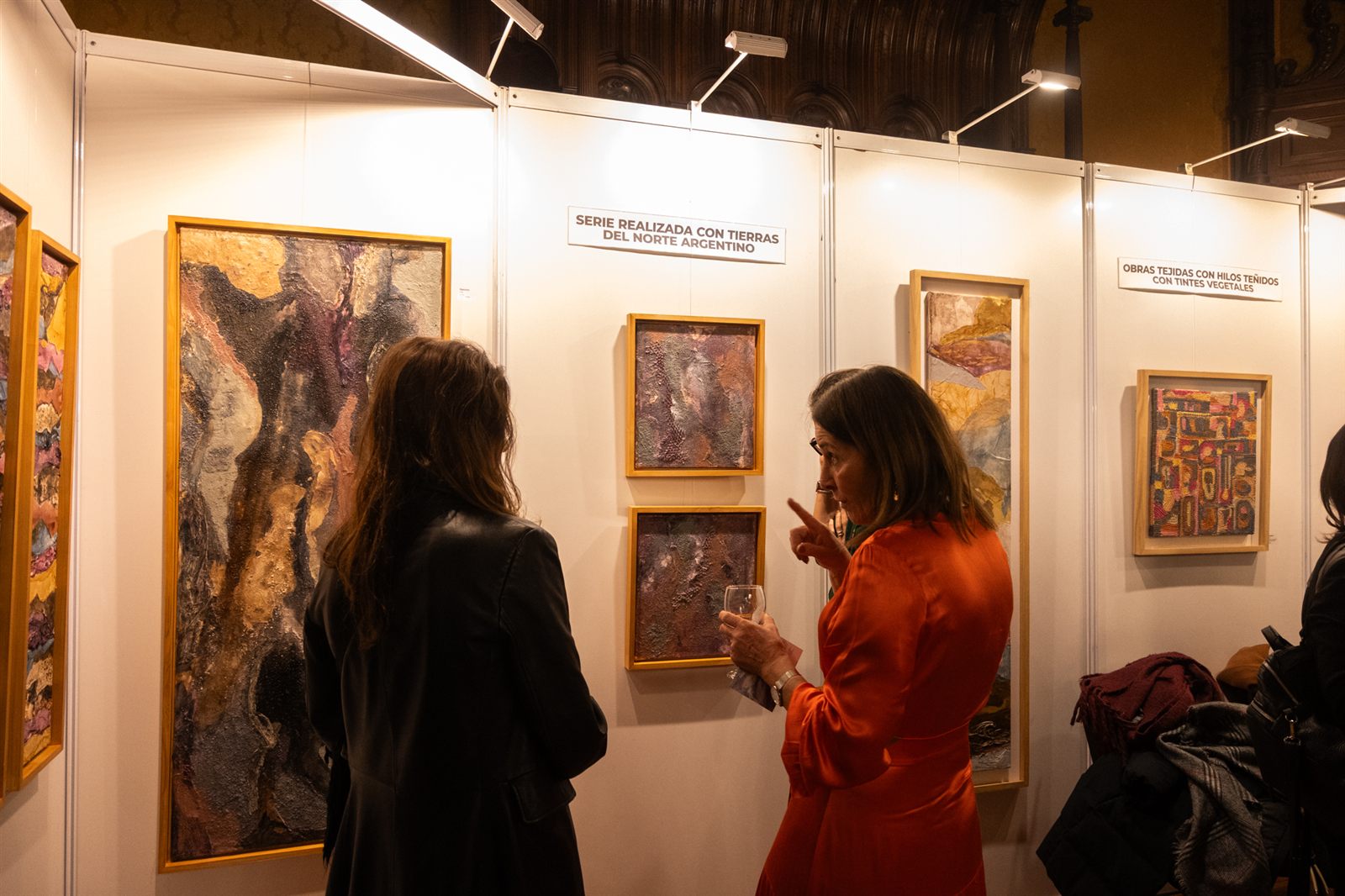 Stand con visitantes dialogando frente a las obras expuestas